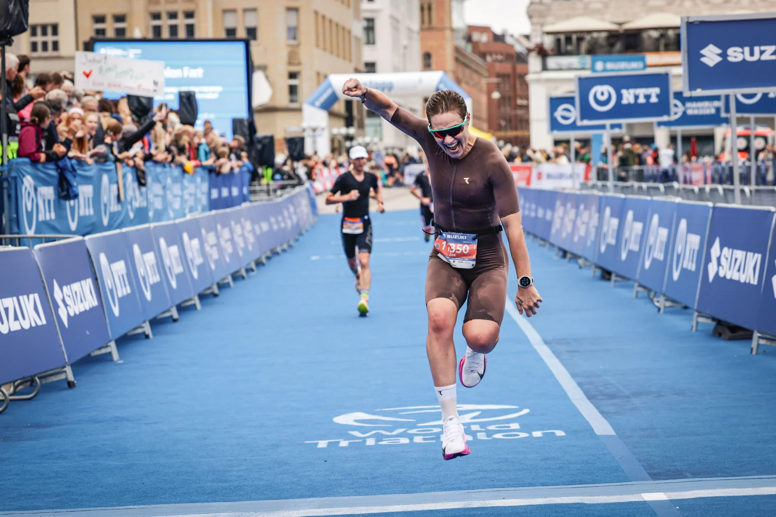 Zoe Barossi triumphierend über die Ziellinie in Hamburg, Arme hoch, World Triathlon Finish
